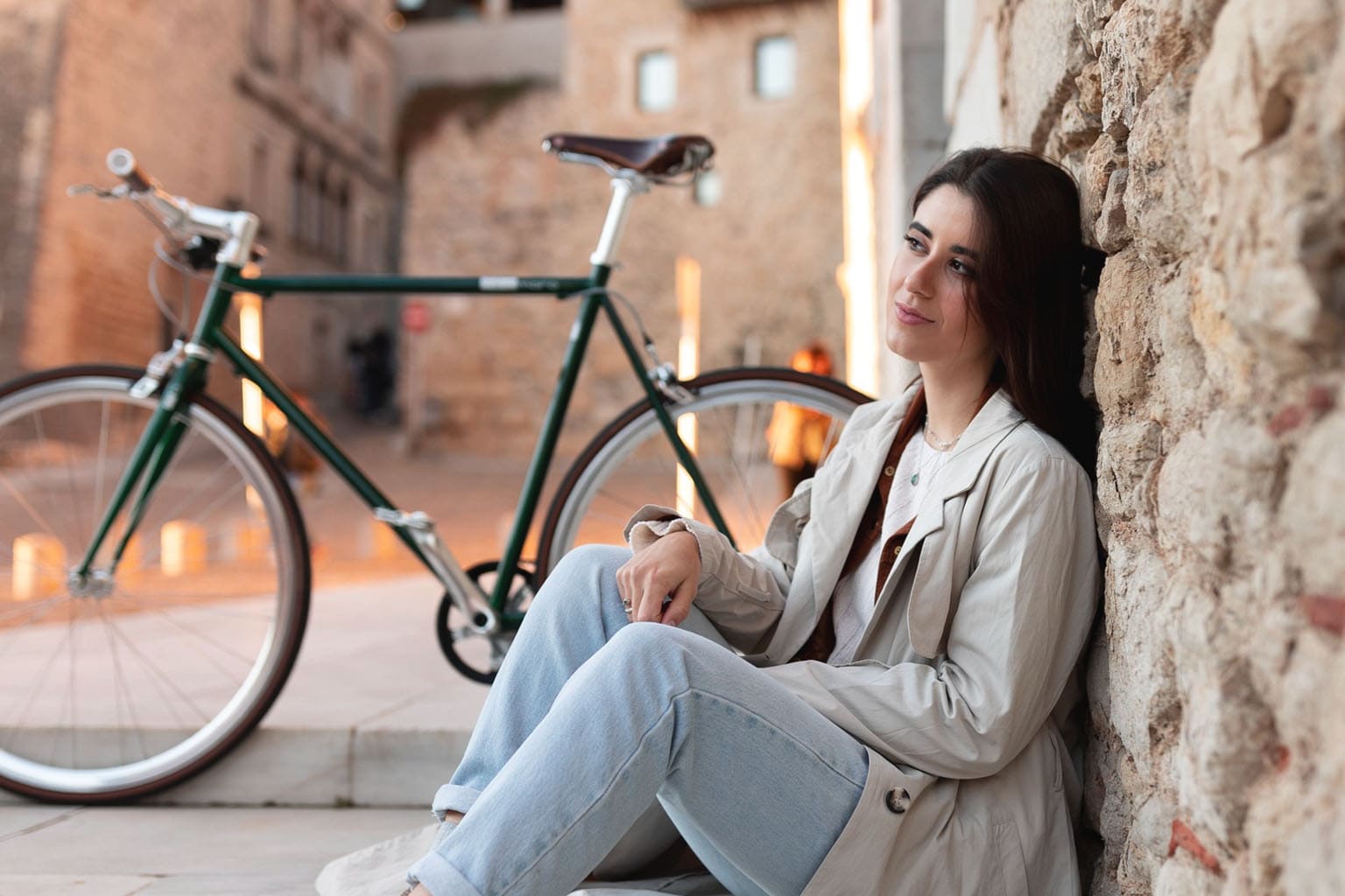Femme assise en ville avec son vélo, prenant un moment pour elle, symbole de bien-être et de temps pour soi