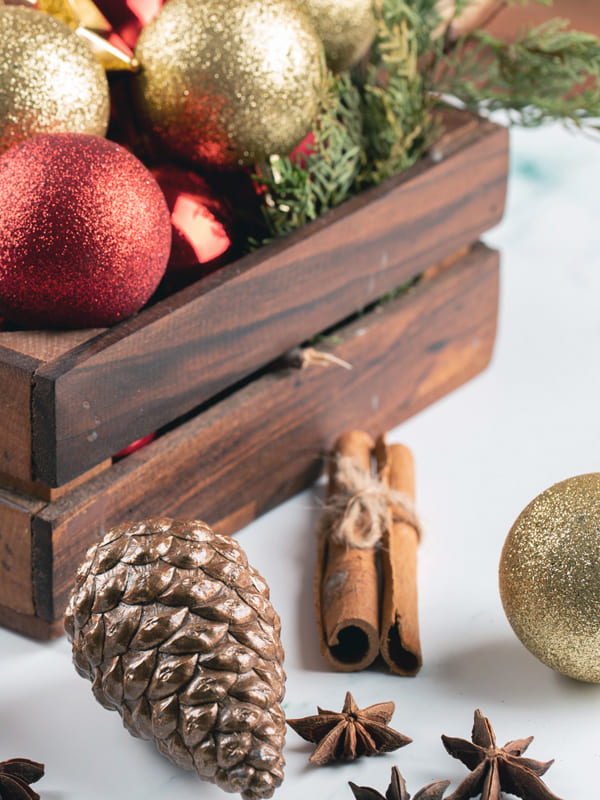 decoration de noel maison interieur boule sapin fete de fain dannee bebymaman Décorations de Noël avec boules rouges et dorées, pommes de pin et cannelle pour une ambiance chaleureuse en famille