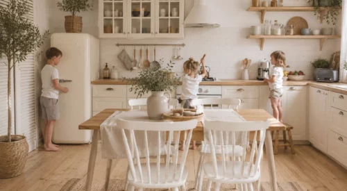 Cuisine familiale lumineuse de style campagne chic où trois enfants participent à la vie de la maison dans une ambiance slow living chaleureuse et organisée.