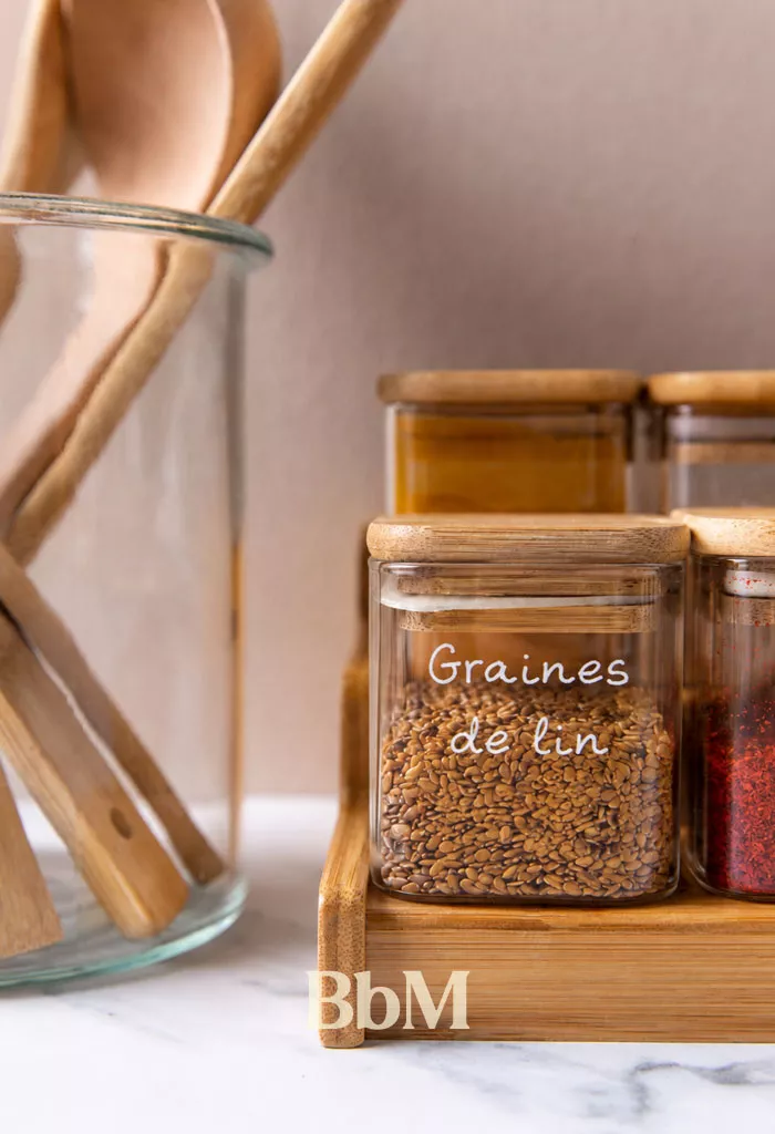 minimalisme domestique cuisine organisee rangements epures slow maman Bocaux en verre étiquetés et ustensiles en bois soigneusement rangés dans une cuisine minimaliste, illustration du minimalisme domestique pour alléger la charge mentale et simplifier le quotidien.