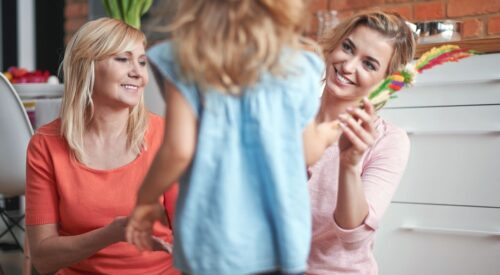 Plusieurs générations de mamans hybrides réunies : grand-mère, maman et enfant partageant un moment complice en famille