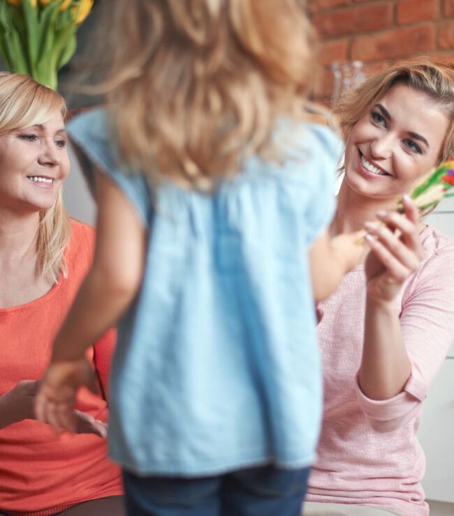 Plusieurs générations de mamans hybrides réunies : grand-mère, maman et enfant partageant un moment complice en famille