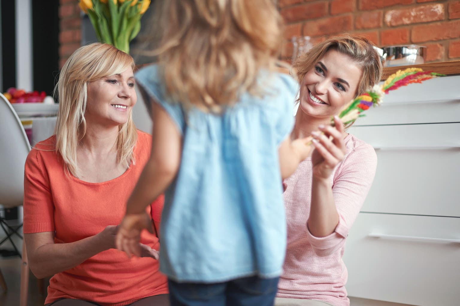 Plusieurs générations de mamans hybrides réunies : grand-mère, maman et enfant partageant un moment complice en famille