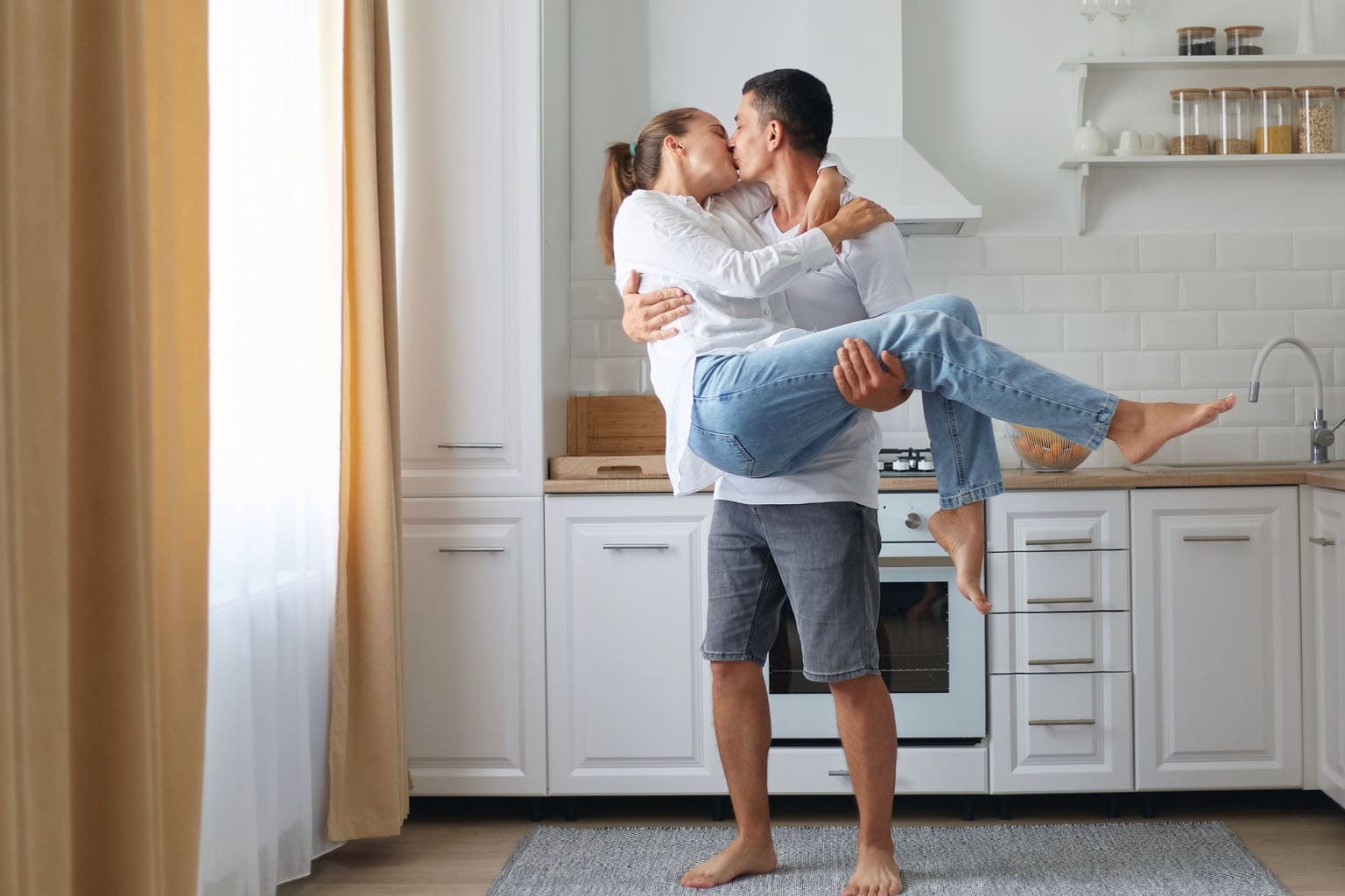 Couple de parents s’embrassant dans la cuisine, moment de complicité au quotidien
