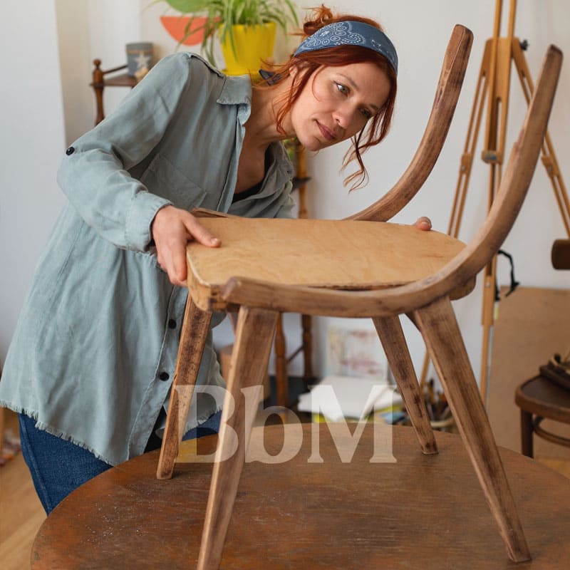 reparation meuble ecoresponsable 2e vie occasion mobilier vintage famille femme bebymaman Femme réorganisant ou rénovant un meuble en bois, symbolisant le renouveau et l’aménagement de printemps.