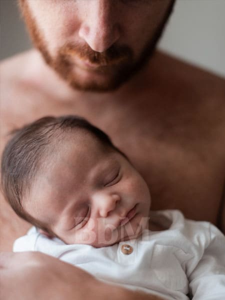 papa naissance de bebe accopagnement maman soutient paternite bebymaman Jeune papa tenant tendrement son nouveau-né endormi contre lui