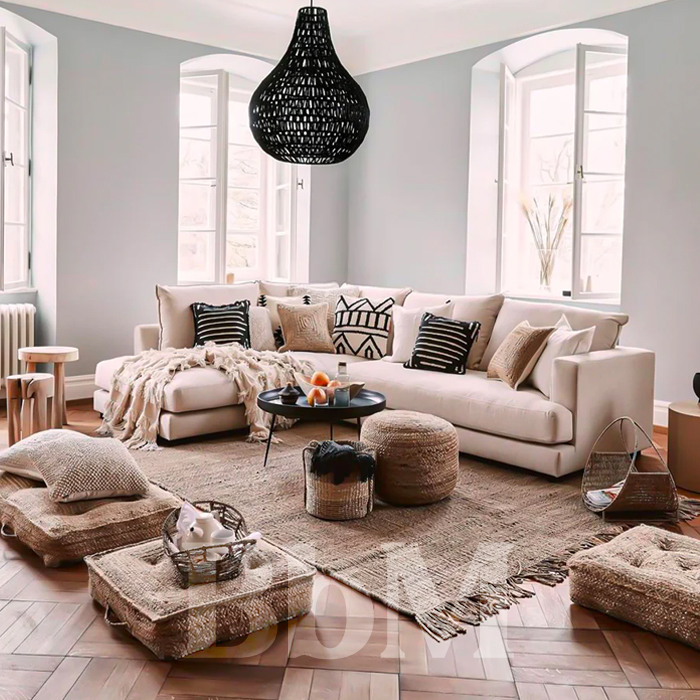 Salon bohème avec canapé blanc d’angle, matières naturelles, tapis en jute, coussins ethniques et poufs en osier.