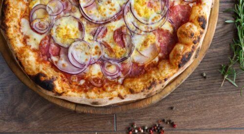 Pizza maison dorée au four avec mozzarella fondue et oignons rouges