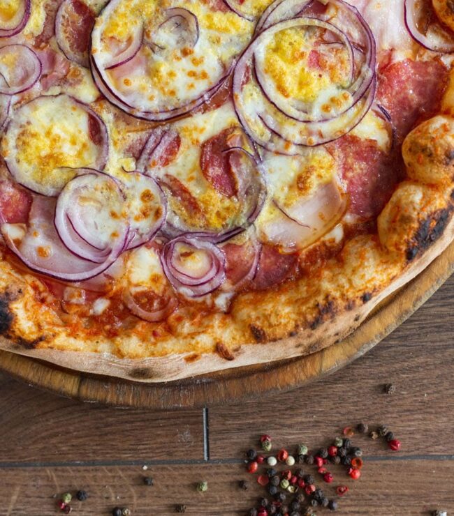 Pizza maison dorée au four avec mozzarella fondue et oignons rouges