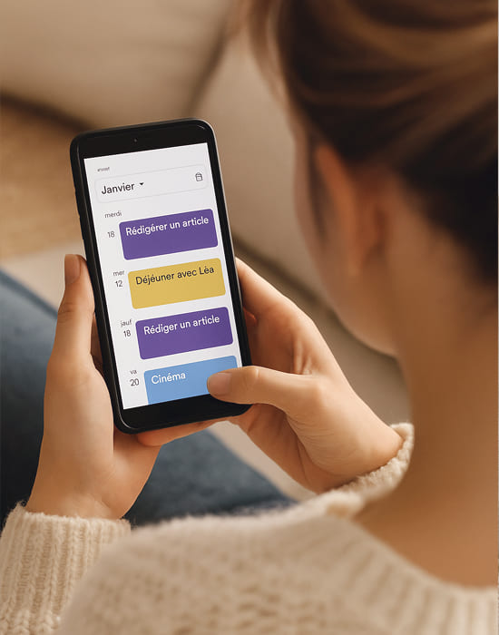 Femme tenant un smartphone affichant son agenda Google avec des créneaux 'Rédiger un article', symbolisant l'importance de planifier du temps pour soi