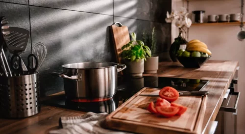 Cuisine familiale avec casserole sur le feu et tomates coupées, illustration de recettes faciles anti-charge mentale