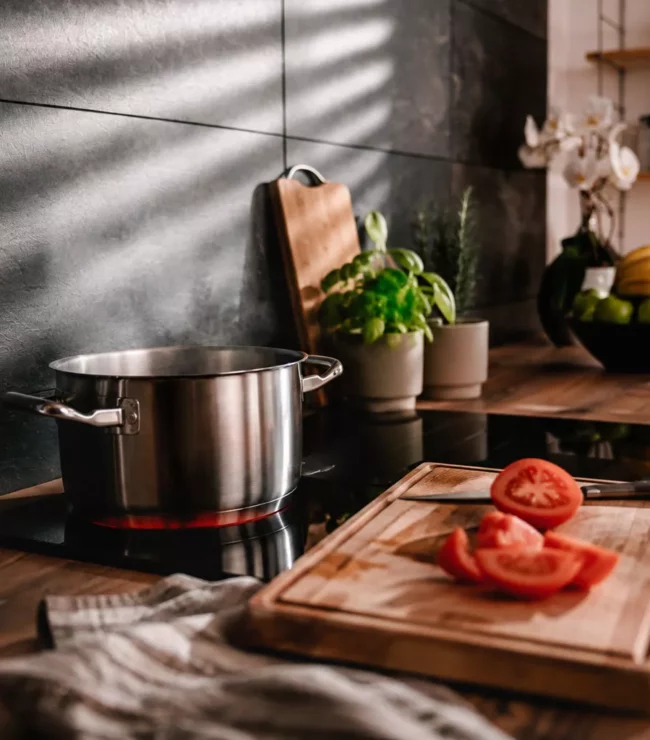 Cuisine familiale avec casserole sur le feu et tomates coupées, illustration de recettes faciles anti-charge mentale