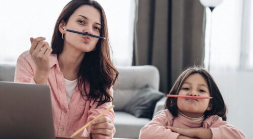 Maman en télétravail avec sa fille à la maison, illustrant le dilemme de la maman hybride entre carrière professionnelle, travail à domicile et vie de famille.