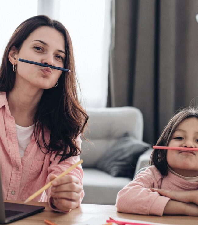 Maman en télétravail avec sa fille à la maison, illustrant le dilemme de la maman hybride entre carrière professionnelle, travail à domicile et vie de famille.