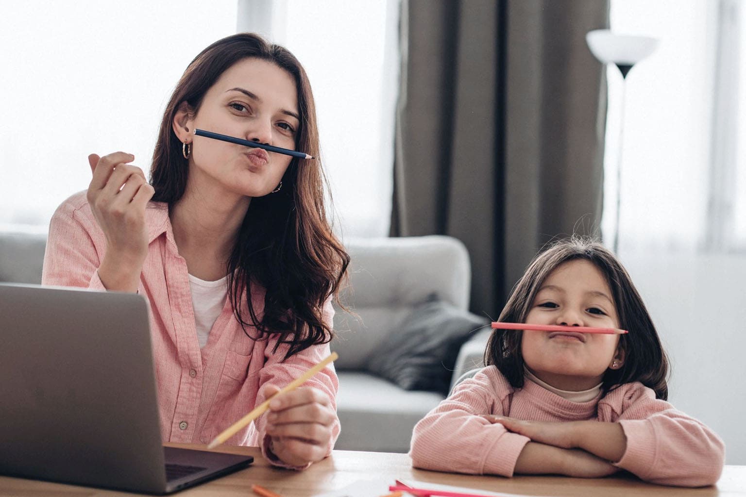 Maman en télétravail avec sa fille à la maison, illustrant le dilemme de la maman hybride entre carrière professionnelle, travail à domicile et vie de famille.