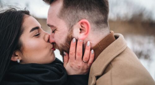 Couple amoureux qui s’embrasse tendrement en extérieur, complicité et bonheur à deux – Be by Maman