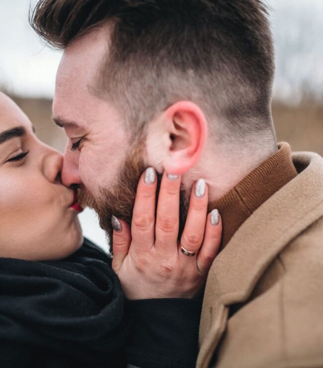 Couple amoureux qui s’embrasse tendrement en extérieur, complicité et bonheur à deux – Be by Maman