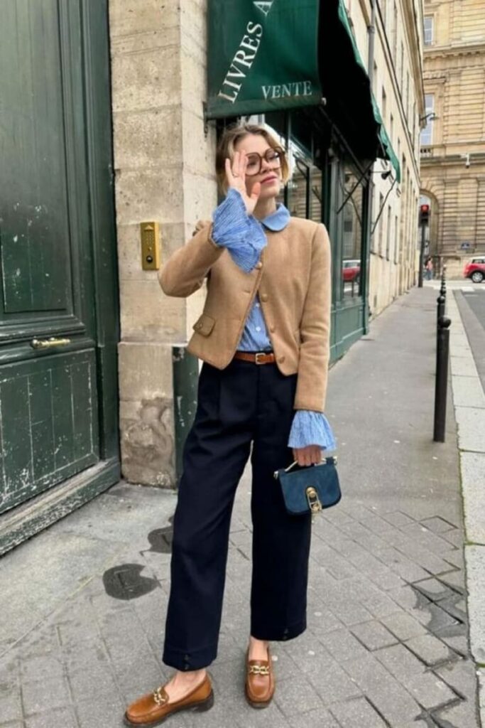look3 automne Femme portant un pantalon large noir, une veste beige et une chemise bleu clair avec des mocassins camel, look vintage chic
