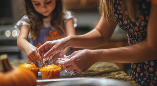 Maman et enfant cuisinant ensemble des muffins au potiron pendant une activité d’automne à la maison