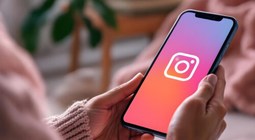 Femme tenant un smartphone affichant le logo d’Instagram à l’écran