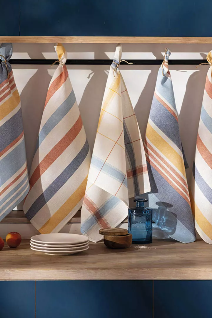 inspiration bord de mer decoration torchon Lot de cinq torchons rayés Océanique en coton aux couleurs sable, terracotta, bleu et jaune suspendus dans une cuisine bord de mer.