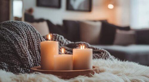 Bougies allumées sur un plaid en laine dans un salon cocooning à la décoration bohème chic