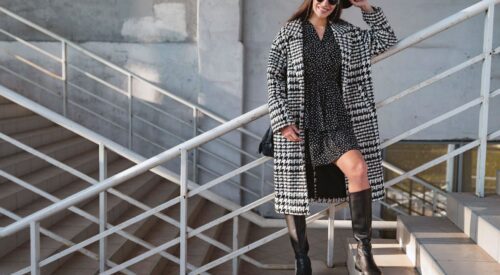 Look femme casual chic avec bottes hautes noires à talon plat, robe fluide et manteau long à carreaux – tendance mode hiver 2025-2026