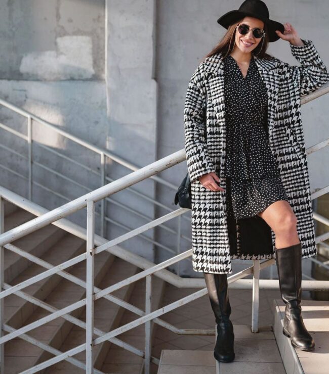 Look femme casual chic avec bottes hautes noires à talon plat, robe fluide et manteau long à carreaux – tendance mode hiver 2025-2026
