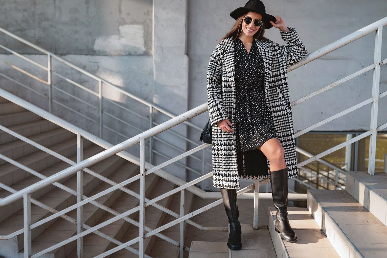 Look femme casual chic avec bottes hautes noires à talon plat, robe fluide et manteau long à carreaux – tendance mode hiver 2025-2026