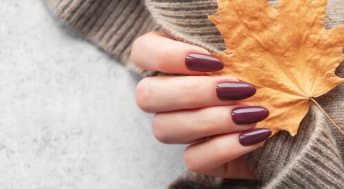Manucure automne mi-saison avec vernis prune, look casual chic et pull en maille beige