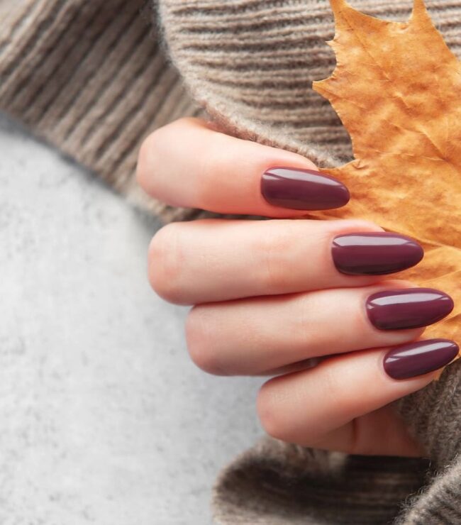 Manucure automne mi-saison avec vernis prune, look casual chic et pull en maille beige