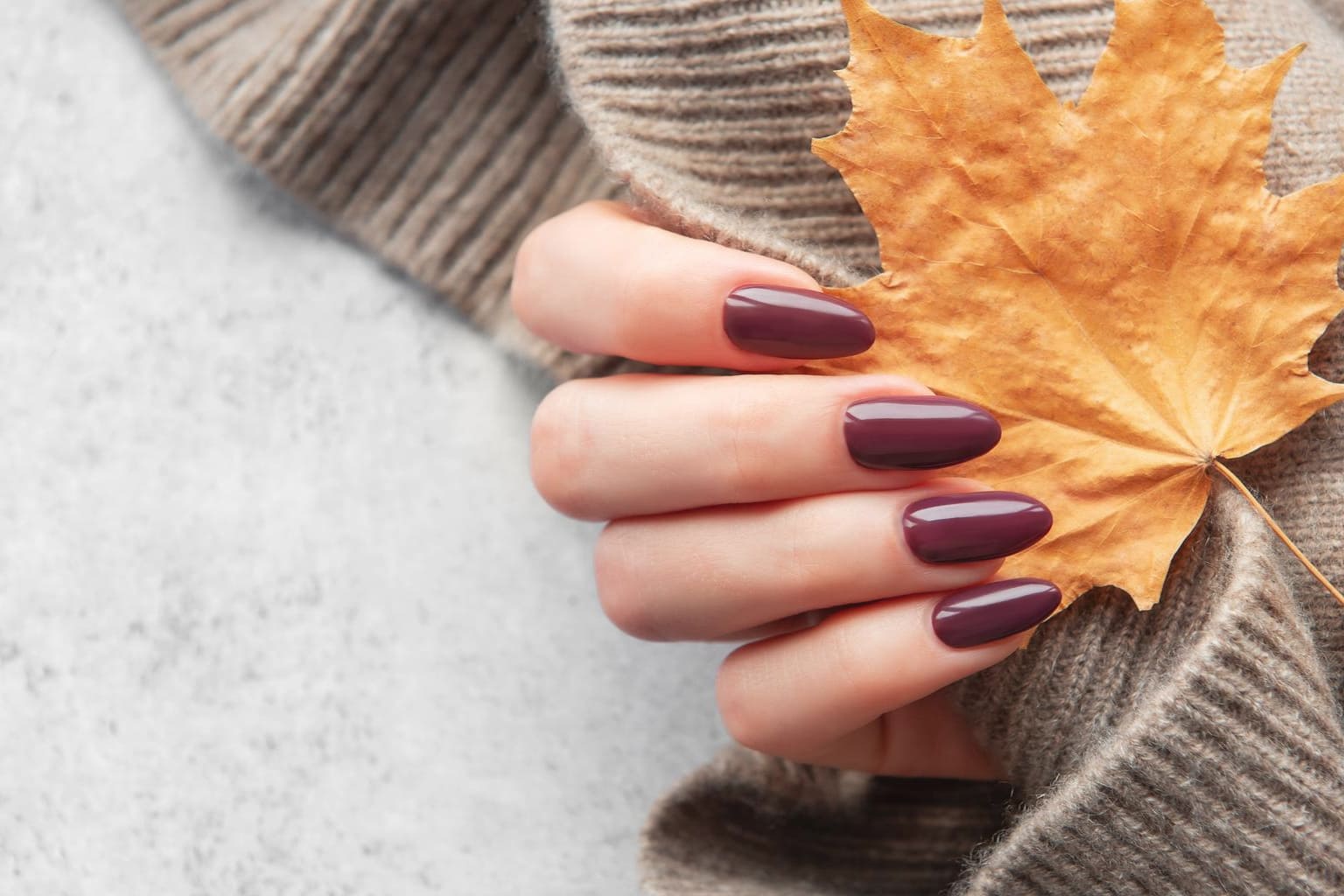 Manucure automne mi-saison avec vernis prune, look casual chic et pull en maille beige