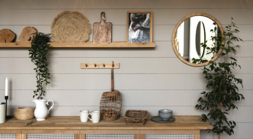 Cuisine moderne chaleureuse avec déco naturelle en bois et rotin, étagère murale stylée et miroir rond.