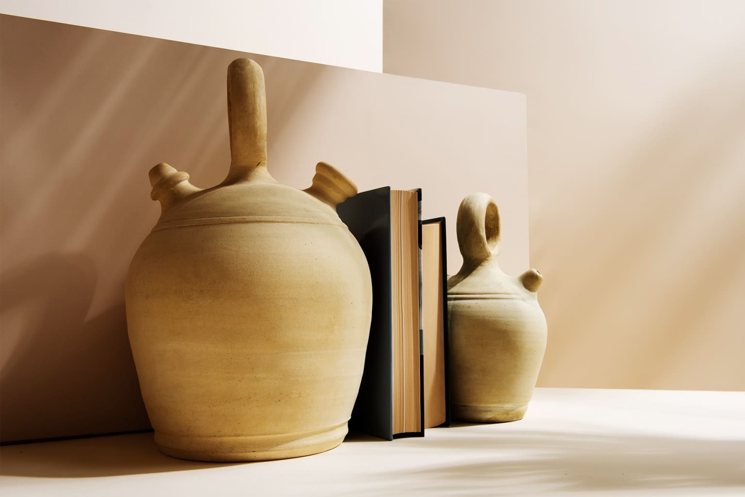 poterie artisanale en terre cuite et livres sur fond beige pour une ambiance slow home