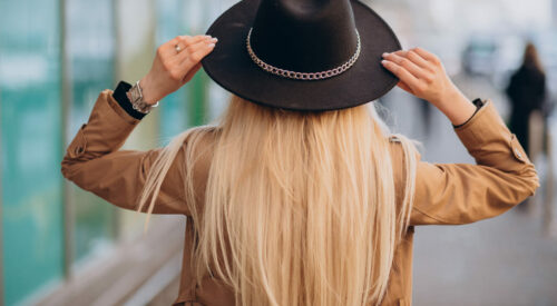 femme de dos avec un chapeau noir et un trench beige, symbole de liberté et de bien-être