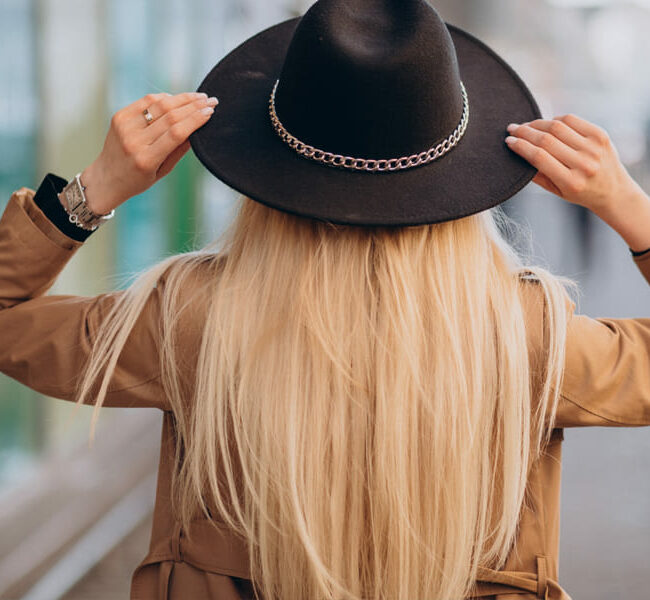 femme de dos avec un chapeau noir et un trench beige, symbole de liberté et de bien-être