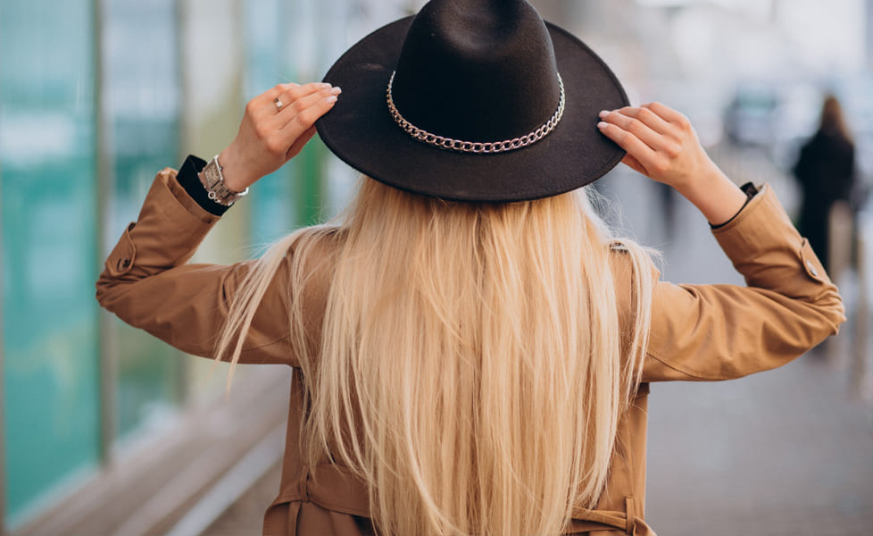 femme de dos avec un chapeau noir et un trench beige, symbole de liberté et de bien-être