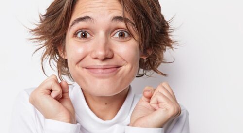 Femme naturelle souriante sans maquillage, cheveux courts, expression spontanée de bien-être et de confiance en soi.
