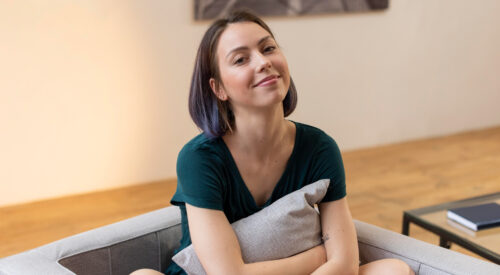 Femme assise, regard pensif, coussin.