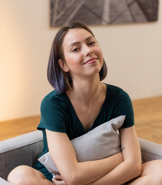 Femme assise, regard pensif, coussin.