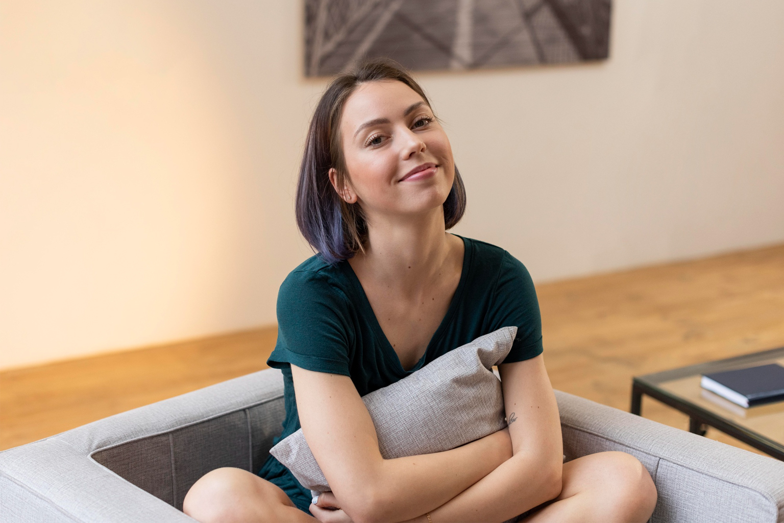 Femme assise, regard pensif, coussin.