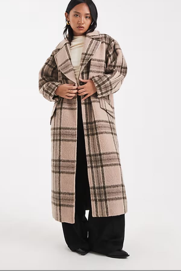 manteau long carreaux asos hiver 2026 Femme portant un manteau long en tissu brossé à carreaux taupe de chez ASOS DESIGN Petite.