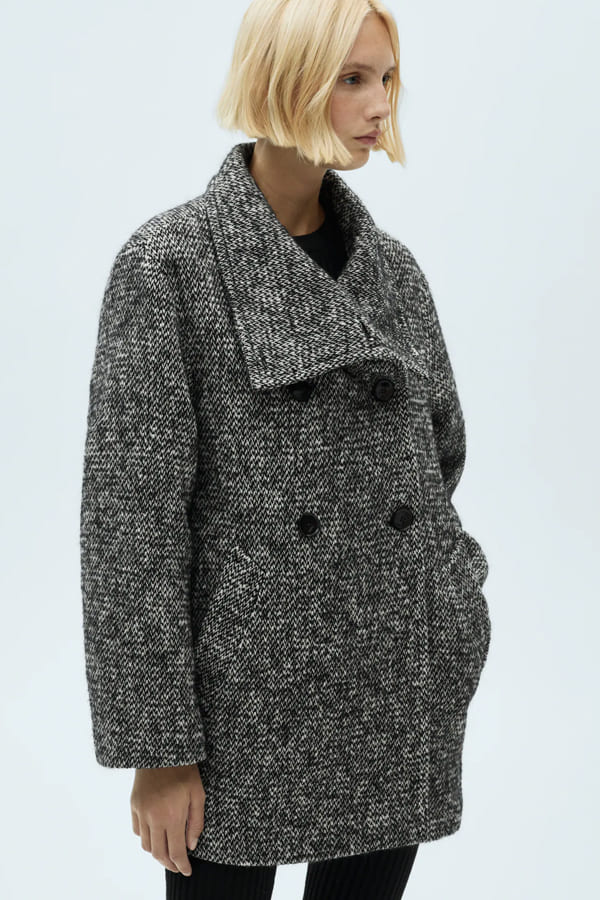 manteaux hiver 2026 chine mango Femme portant un manteau chiné gris à double boutonnage de chez Mango.