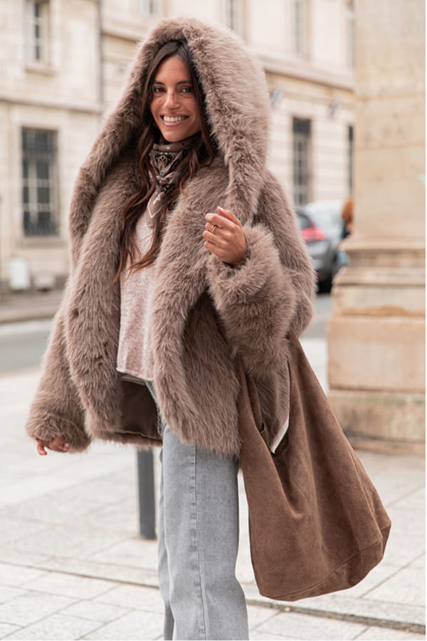 manteaux hiver 2026 fourrure prettywire Femme portant un manteau en fausse fourrure taupe Anaé de chez Pretty Wire dans une rue urbaine.