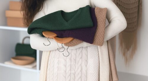 Femme tenant des vêtements d’hiver tendance dans des tons vert olive, aubergine et beige café