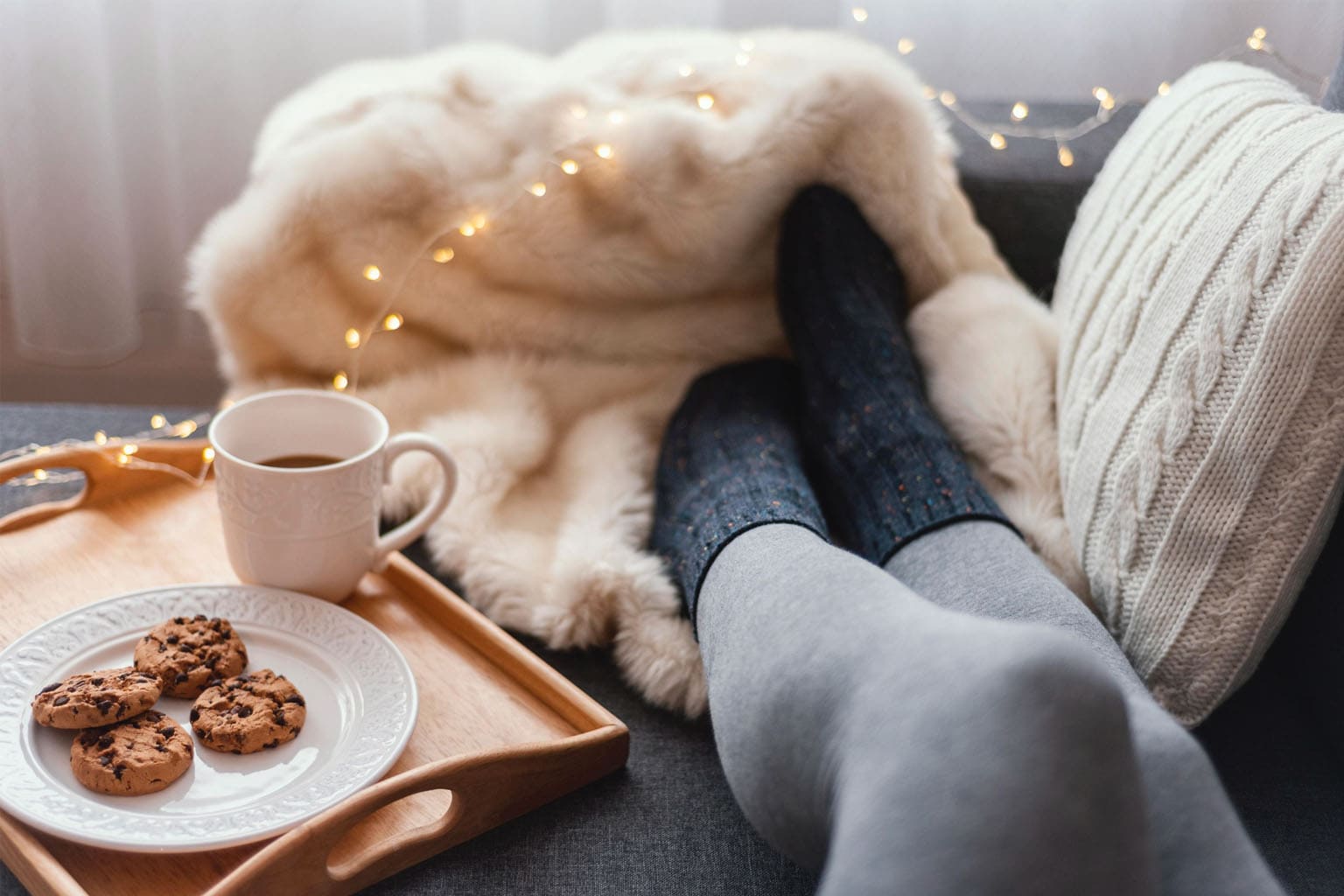 Moment cocooning d’hiver pour maman : pause bien-être sur le canapé avec plaid, café chaud et cookies, symbole de slow life, détente et temps pour soi en janvier