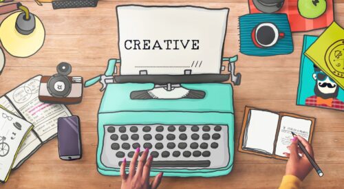 Vue d’un bureau créatif avec une machine à écrire turquoise, des carnets, un café et des éléments graphiques dessinés, symbolisant l’univers d’un blogzine.