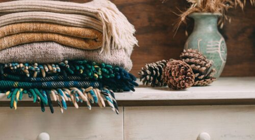 Plaids et tricots d’hiver pliés dans des tons chauds, ambiance cosy et cocooning.