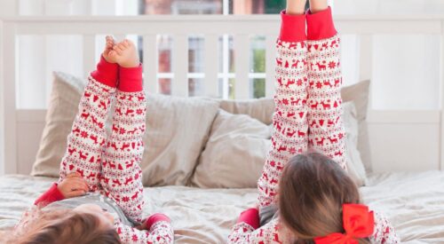 Enfants en pyjama d’hiver allongés sur un lit, moments cocooning en famille à la maison, rituels d’hiver chaleureux sans partir à la montagne