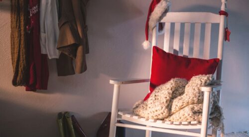 Fauteuil blanc cosy avec plaid en laine et coussin rouge, ambiance maison après Noël, déco hivernale apaisante et slow home en janvier